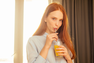 beautuful redhaired ginger woman useing eco tubes for drink smoothie at home,sunset sun light background