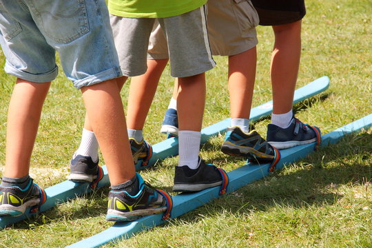 Children using together a pair of ski during summer games
