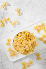 Farfalle pasta in a white bowl on a light table. Italian cuisine. Top view