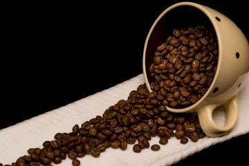 Coffee beans spread around coffee mugs on a black background