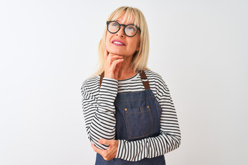 Middle age woman wearing apron and glasses standing over isolated white background with hand on...