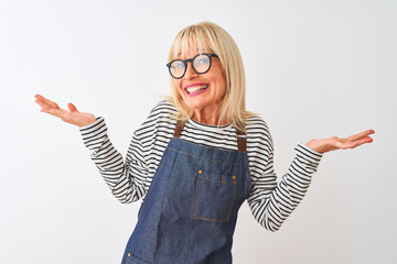 Middle age woman wearing apron and glasses standing over isolated white background clueless and...