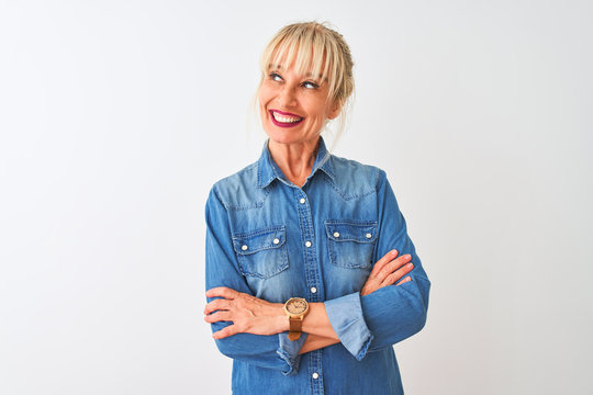 Middle age woman wearing casual denim shirt standing over isolated white background smiling looking to the side and staring away thinking.