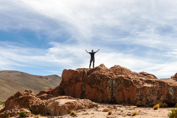 Man on the top of the cliff with hands up