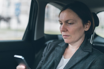 Businesswoman text messaging on mobile phone in car