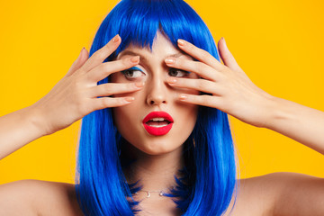 Portrait closeup of seductive beautiful woman wearing blue wig looking aside and covering her face