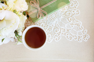 Beautiful top view flat lay a cup of tea with lace decorations flower bouquet and green gift box for wedding background or valentines concept