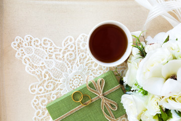 Beautiful top view flat lay a cup of tea with lace decorations flower bouquet and green gift box for wedding background or valentines concept