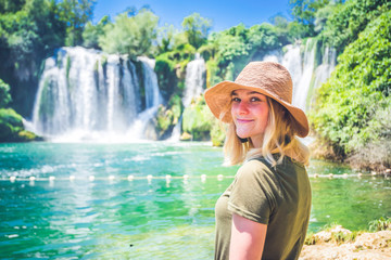 Kravice waterfall on the Trebizat River in Bosnia and Herzegovina. Young pretty woman smile enjoy the beauty of nature