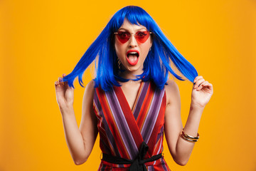 Portrait of cute shocked woman wearing blue wig and sunglasses looking at camera and shouting