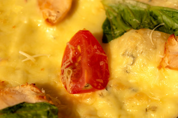 Big tomato, salad and meat on pizza closeup