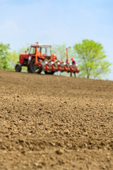 Fototapeta premium Farmer repairing tractor with seeder in field