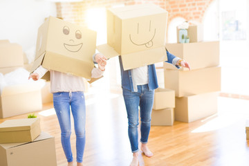 Fototapeta na wymiar Couple having fun at new apartment wearing boxes with funny faces over head