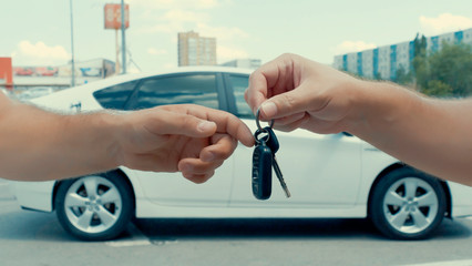 Selling and buying a car. Seller transfers car keys to new owner.