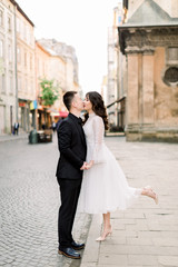 Lovely Asian couple walk and kissing in the city. Man is in black luxury suit, woman in white stylish dress