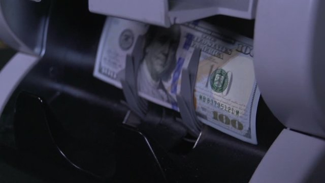 Super slow motion Male, female hand pulls out US dollar bills from money counter machine. Currency, detector counting