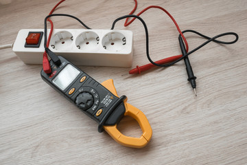 Clamp meter with power strip on the wooden table