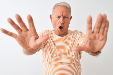 Naklejka premium Senior grey-haired man wearing striped t-shirt standing over isolated white background doing stop gesture with hands palms, angry and frustration expression