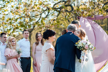 Bride and groom after wedding ceremony. Parents welcome newlyweds to marry. Stylish happy smiling...