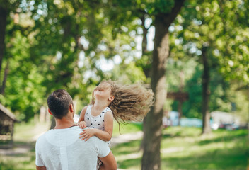 Father and his little girl playing together in the park in summer day.