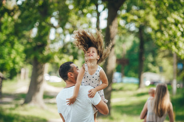Happy young family father, mother and children having fun outdoors, playing together in summer park, countryside.