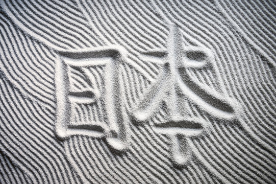 Japanese Zen garden with the Chinese characters for Nihon (English translation: Japan) written in textured white sand raked with abstract wave patterns