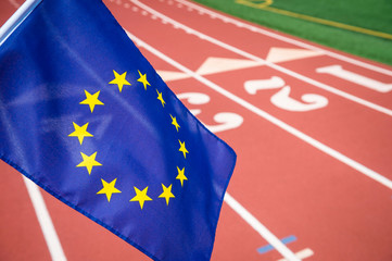 European Union flag flying in front of a red athletic track background with copy space for...
