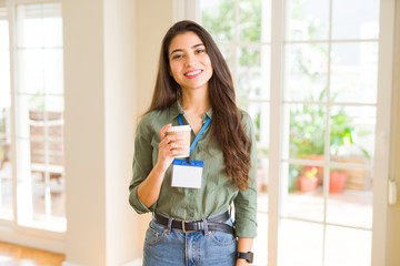 Young beautiful business woman wearing an id card drinking a cup of coffee