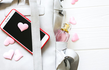 Phone, stylish bag and perfumes on white background. Beautiful flat lay with hearts. The best present for the girl. Woman's or mother's day idea.