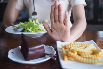 One woman is controlling weight. Cake and French Fries out and choose to eat vegetable carvings.