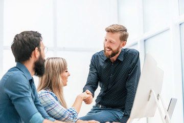 young professionals shaking hands in the workplace