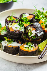 Vegan sushi rolls with black rice, avocado and sweet potato on white dish. Vegan food concept.