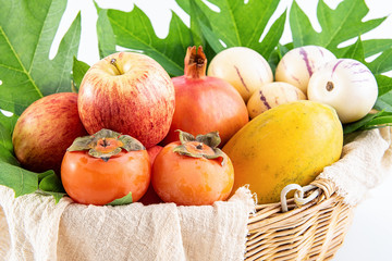 Rattan basket with fresh fruits on a white background