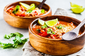 Traditional mexican bean soup with meat and cheese in wooden bowl, white background. Mexican food concept.