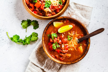 Traditional mexican bean soup with meat and cheese in wooden bowl, white background. Mexican food concept.