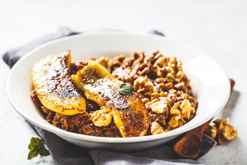Chocolate oatmeal porridge with fried banana and walnut in white plate.