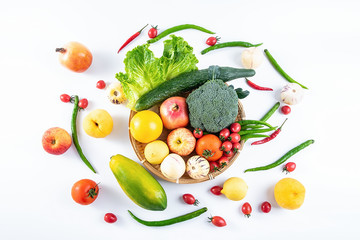 A bamboo plate filled with fresh seasonal vegetables and fruits on a white background