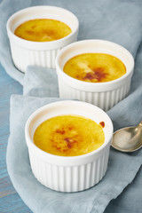 Crema catalana, Spanish dessert in three ramekin on blue table, vertical