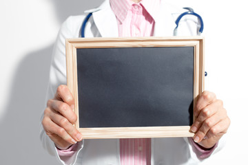 The doctor in a white coat holds an empty sign for inscription. 