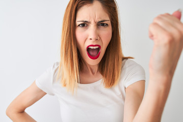 Beautiful redhead woman wearing casual t-shirt standing over isolated white background annoyed and frustrated shouting with anger, crazy and yelling with raised hand, anger concept
