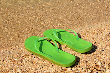 Fototapeta na wymiar Flip flops on the seashore. Shoes by the sea