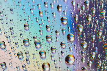 Water drops with reflection of the rainbow. Colorful abstract background. Blue, green and red abstract rainbow background. Closeup, selective focus