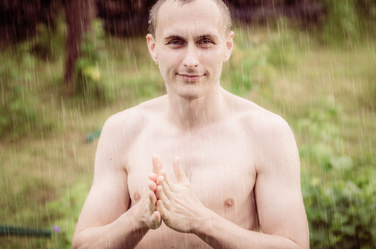 Portrait of a naked man standing in the rain