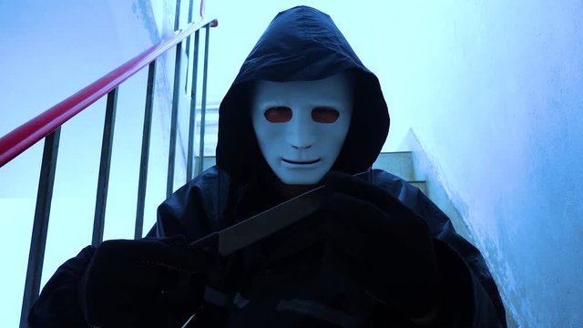 murder, kill and people concept - Criminal or murderer in black wearing a white mask holding knife inside a condo at crime scene 