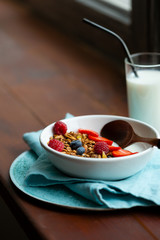 Breakfast bowl with granola on wooden window, healthy food