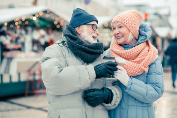 Elderly couple clanging cups of coffee and smiling