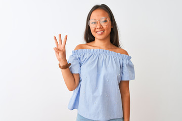 Fototapeta premium Young chinese woman wearing blue t-shirt and glasses over isolated white background showing and pointing up with fingers number three while smiling confident and happy.