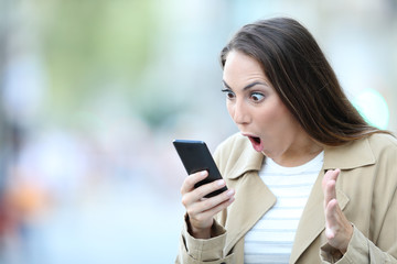 Fototapeta na wymiar Shocked woman finding surprising news on phone