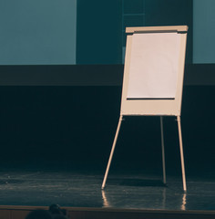 flipchart in front of a white screen on the stage of the conference room