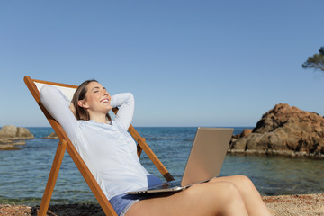 Happy entrepreneur with a laptop relaxing on the beach